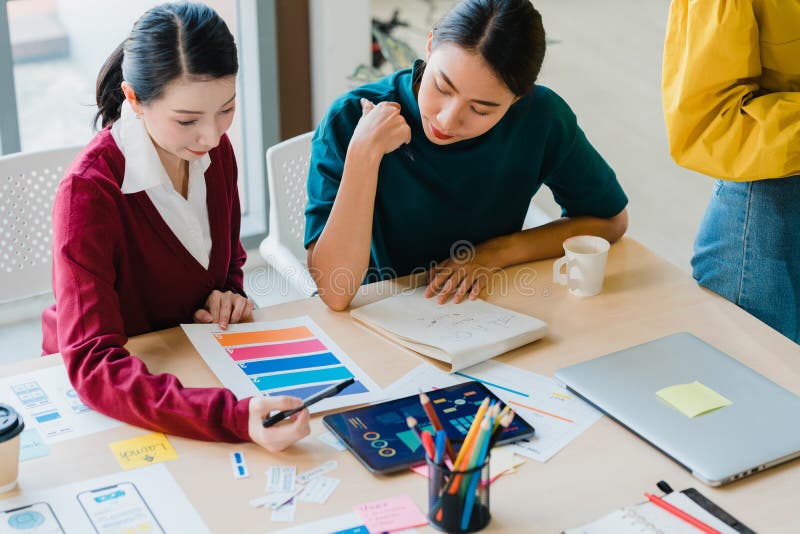 Grupa azjatyckich młodych kreatywnych ludzi japońska szefowa pedagogiki stażystka lub nowa pracownica hispanic dziewczyna pomagają