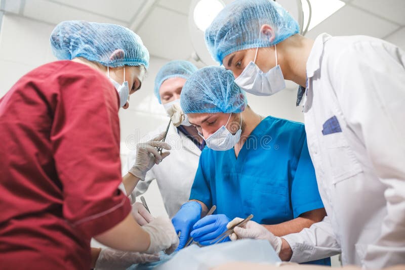 Grupa chirurdzy przy pracy dzia?aniem w chirurgicznie theatre Resuscitation medycyny ochronnych masek drużynowy jest ubranym trzy obrazy stock Grupa chirurdzy przy pracy dzia?aniem w chirurgicznie theatre Resuscitation medycyny ochronnych masek drużynowy jest ubranym trzy obrazy stock