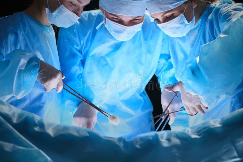 Grupa chirurdzy przy pracą w operacyjnym teatrze tonował w błękicie