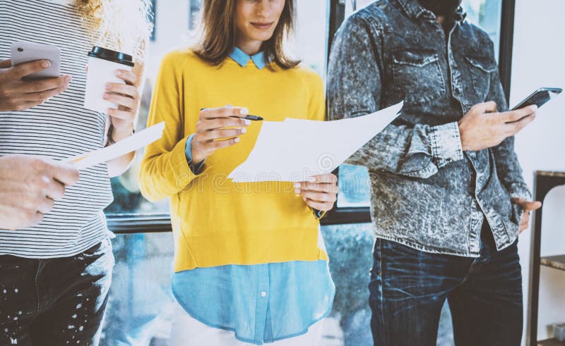 Grupa coworkers przyjaciele stoi przód i dyskutuje biznesowego pomysł okno w biurze Młoda kobieta trzyma a fotografia stock Grupa coworkers przyjaciele stoi przód i dyskutuje biznesowego pomysł okno w biurze Młoda kobieta trzyma a fotografia stock