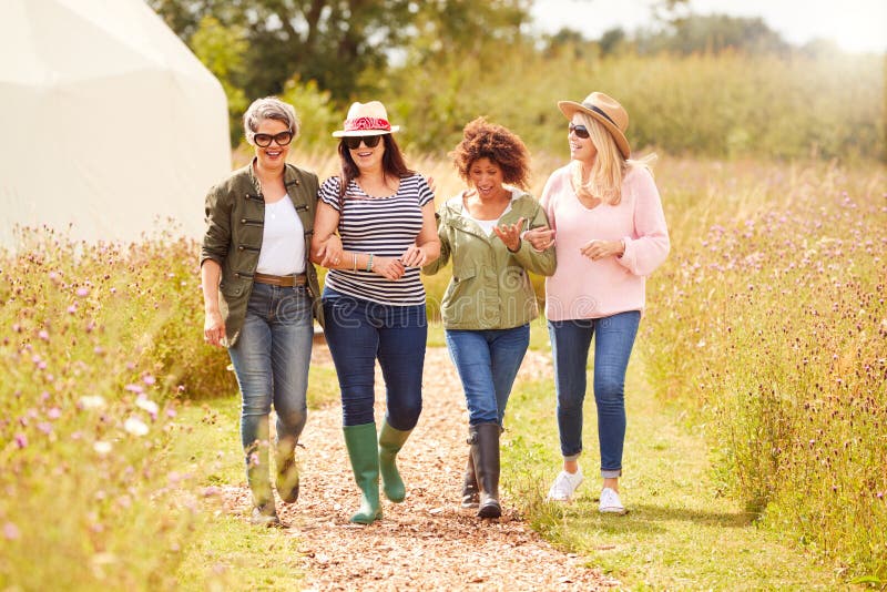 Group Of Mature Female Friends Walking Along Path Through Yurt Campsite. Group Of Mature Female Friends Walking Along Path Through Yurt Campsite