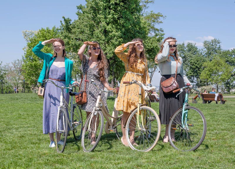 Grupa dziewczyny w starej modzie ubiera gotowego dla jeździć na rowerze z rocznika bicyklem podczas plenerowego festiwalu Retro r obrazy stock Grupa dziewczyny w starej modzie ubiera gotowego dla jeździć na rowerze z rocznika bicyklem podczas plenerowego festiwalu Retro r obrazy stock