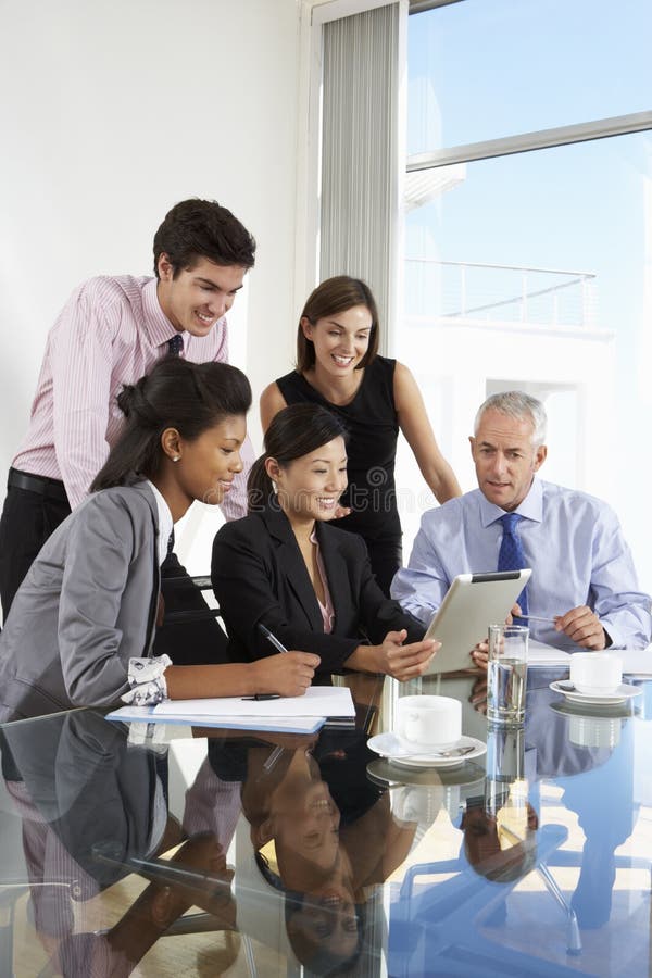 Group Of Business People Having Meeting Around Tablet Computer At Glass Table. Group Of Business People Having Meeting Around Tablet Computer At Glass Table