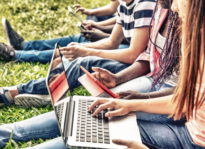 Grupa mieszani rasa nastolatkowie używa laptopy i smartphones out obrazy stock Grupa mieszani rasa nastolatkowie używa laptopy i smartphones out obrazy stock