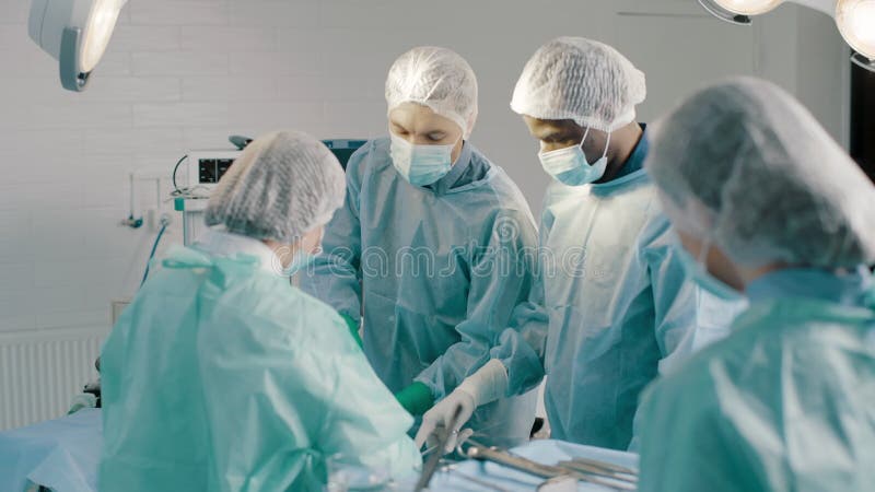 Grupa mieszanych profesjonalnych chirurgów i pielęgniarek w mundurach wykonujących operację przeszczepu serca