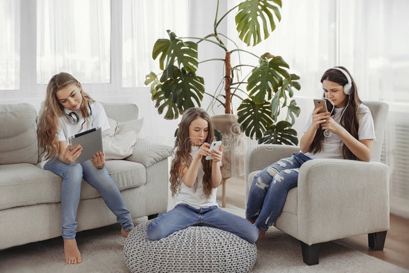 Grupa nastoletnie dziewczyny używa gadżety Dzieciaki z telefonami, pastylki, smartphones i hełmofony, zdjęcie royalty free Grupa nastoletnie dziewczyny używa gadżety Dzieciaki z telefonami, pastylki, smartphones i hełmofony, zdjęcie royalty free