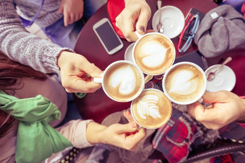 Grupa przyjaciele pije cappuccino przy kawowego baru restauracją