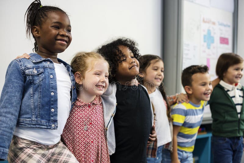 Grupa różnorodni dziecinów ucznie stoi wpólnie w clas