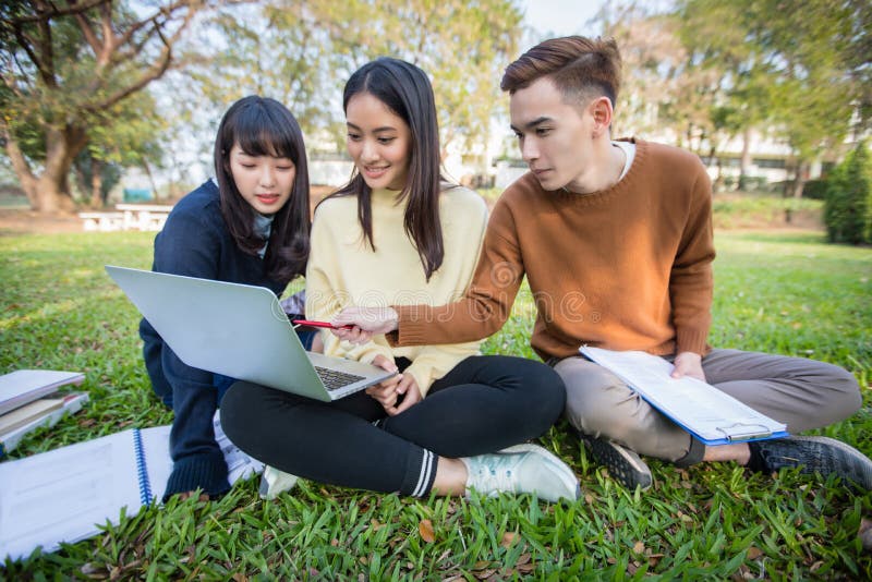 Grupa studenta uniwersytetu azjatykci obsiadanie na zielonej trawie W zdjęcia royalty free Grupa studenta uniwersytetu azjatykci obsiadanie na zielonej trawie W zdjęcia royalty free