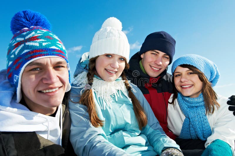 Happy young smiling student people group in warm clothing lying on snow at winter outdoors. Happy young smiling student people group in warm clothing lying on snow at winter outdoors