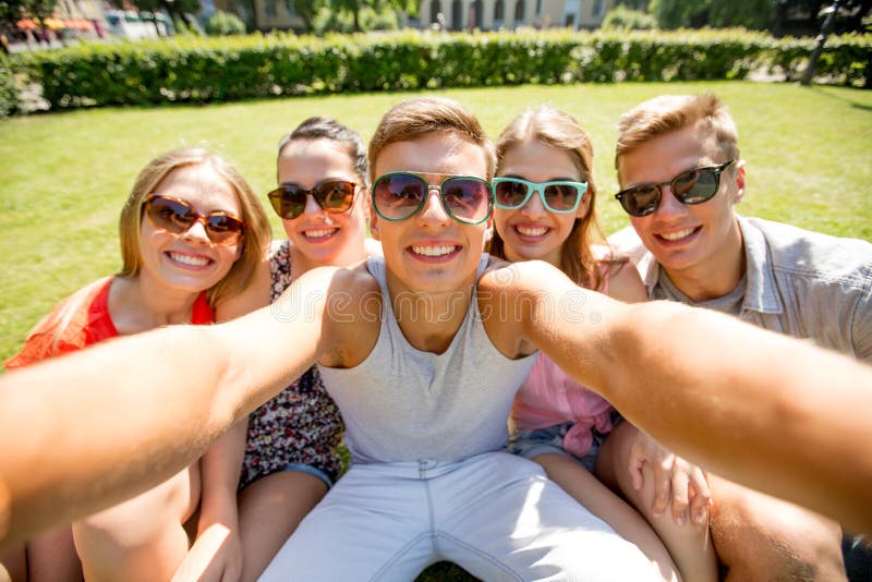Grupa uśmiechnięci przyjaciele robi selfie w parku fotografia royalty free