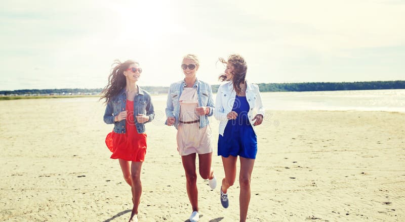 Grupa uśmiechnięte kobiety w okularach przeciwsłonecznych na plaży