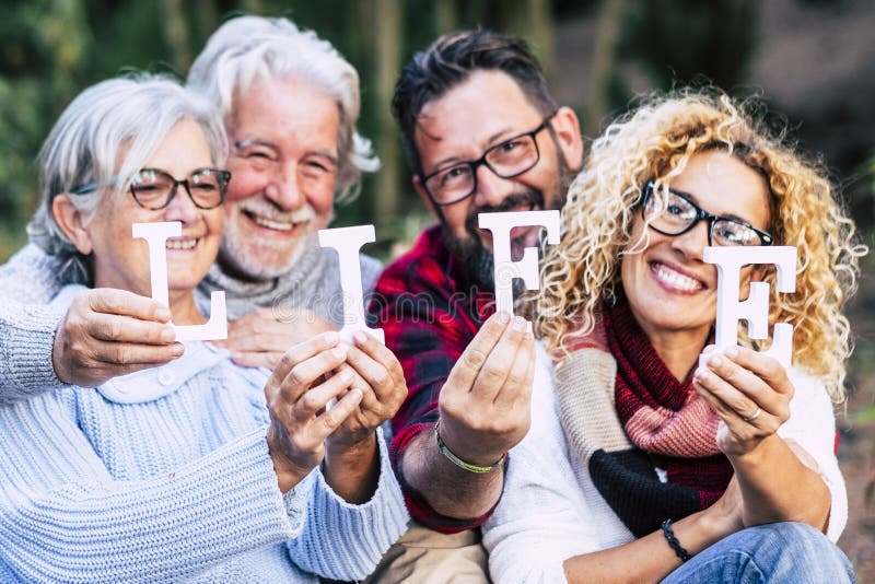 Grupa wieków mieszanych pokolenia uśmiechają się i pokazują listy z żywym słowem - szczęśliwy styl życia cieszący się z zewnątrz