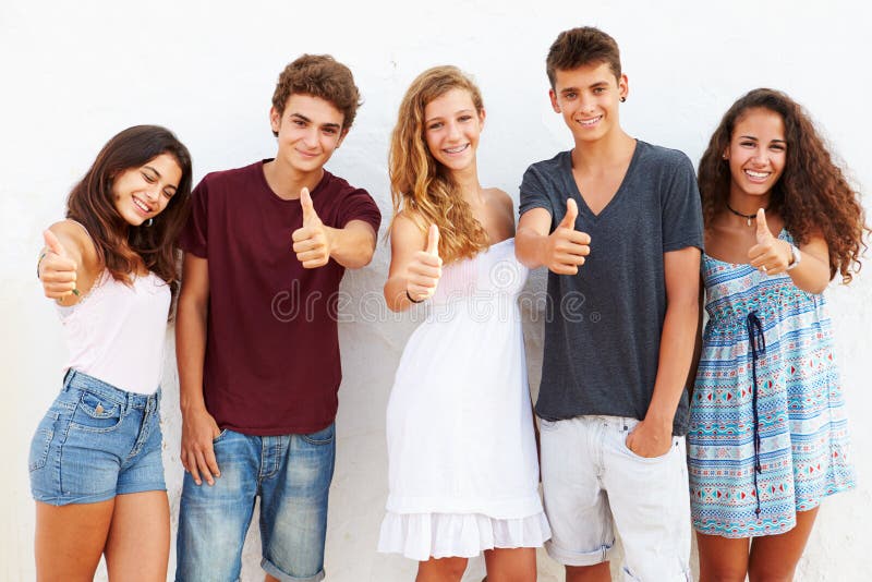 Grupo adolescente que inclina-se contra a parede que dá os polegares acima fotografia de stock Grupo adolescente que inclina-se contra a parede que dá os polegares acima fotografia de stock