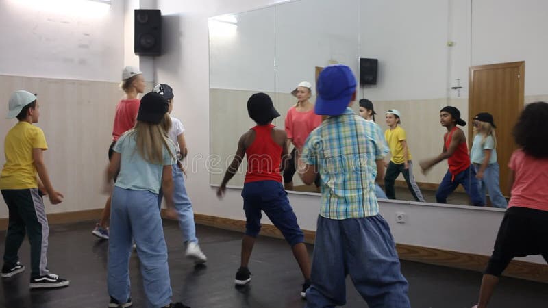Grupo de alegres tuits con profesora de hip hop practicando en estudio de baile moderno