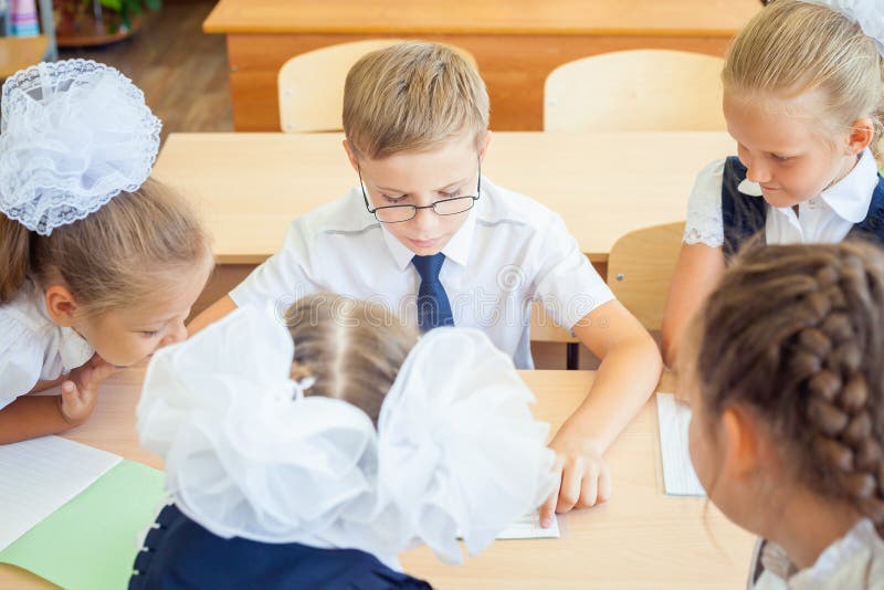 Grupo de alunos na sala de aula da escola que senta-se na mesa fotografia de stock royalty free Grupo de alunos na sala de aula da escola que senta-se na mesa fotografia de stock royalty free