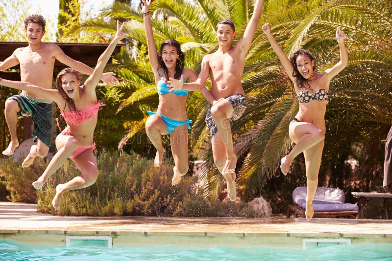 Grupo de amigos adolescentes que saltan en piscina foto de archivo libre de regalías Grupo de amigos adolescentes que saltan en piscina foto de archivo libre de regalías