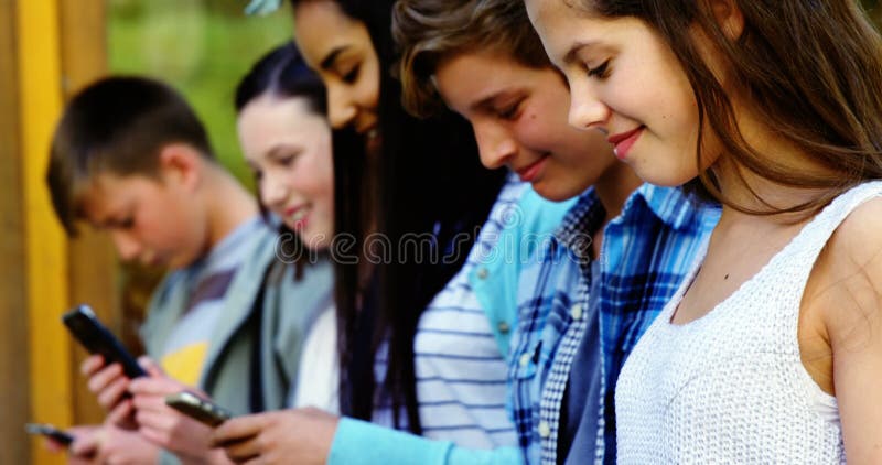 Grupo de amigos da escola que usam o telefone celular fora da escola