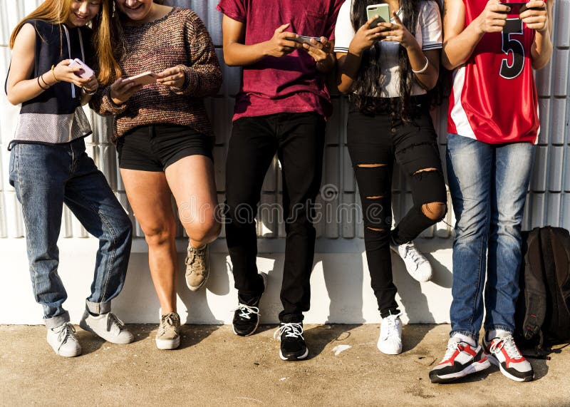 Grupo de amigos jovenes del adolescente que se enfrían hacia fuera junto usando concepto social del smartphone medios