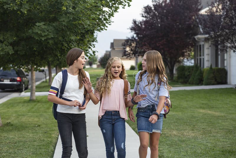 Group of young female friends and students talking together as they walk home school for the day. Being social and building friendships during their school years. Group of young female friends and students talking together as they walk home school for the day. Being social and building friendships during their school years