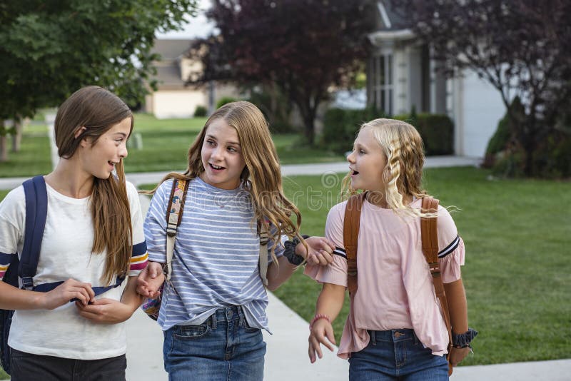 Group of young female friends and students talking together as they walk home school for the day. Being social and building friendships during their school years. Group of young female friends and students talking together as they walk home school for the day. Being social and building friendships during their school years