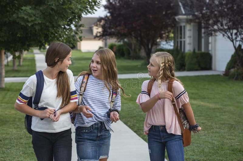 Group of young female friends and students talking together as they walk home school for the day. Being social and building friendships during their school years. Group of young female friends and students talking together as they walk home school for the day. Being social and building friendships during their school years