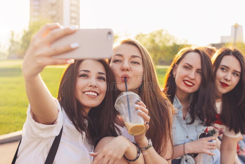 Grupo de amigos de meninas despreocupados felizes novos que fazem o selfie na rua da cidade do verão, fundo do tempo do por do so imagens de stock royalty free Grupo de amigos de meninas despreocupados felizes novos que fazem o selfie na rua da cidade do verão, fundo do tempo do por do so imagens de stock royalty free