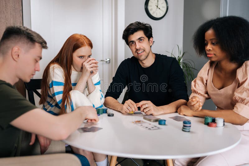 Amigos multiétnicos felizes tendo jogos de cartas por tempo