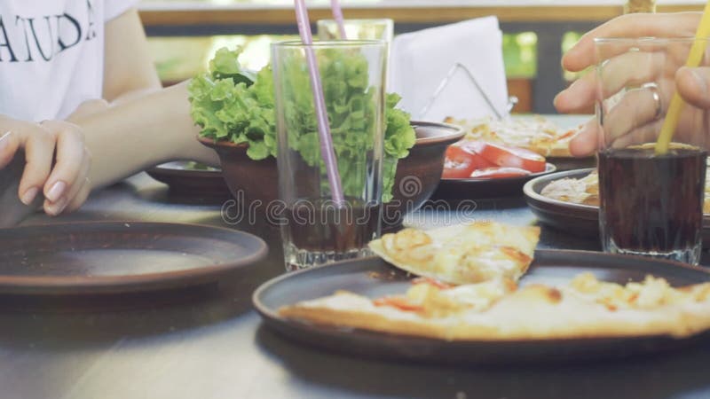 Grupo de amigos novos que comem a pizza em um exterior