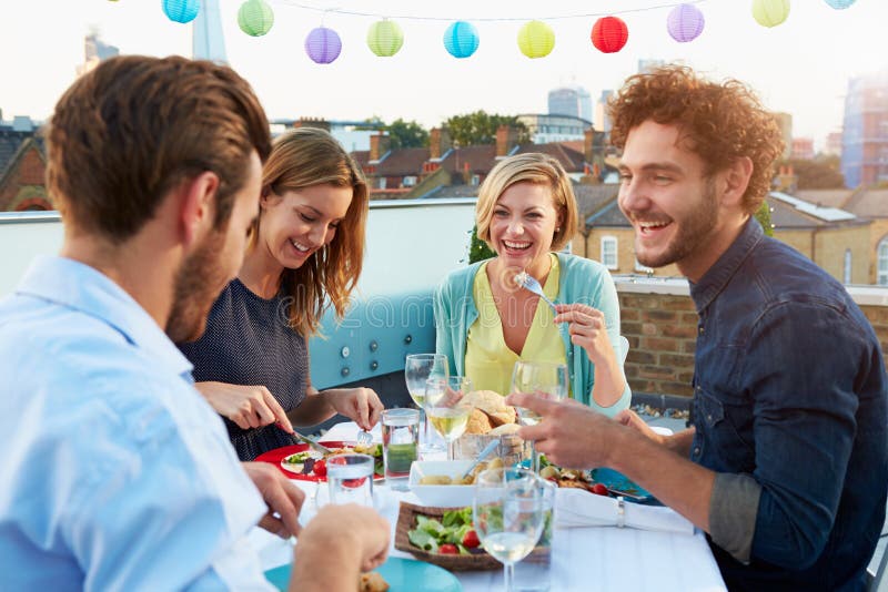 Grupo de amigos que comen la comida en terraza del tejado fotografía de archivo Grupo de amigos que comen la comida en terraza del tejado fotografía de archivo