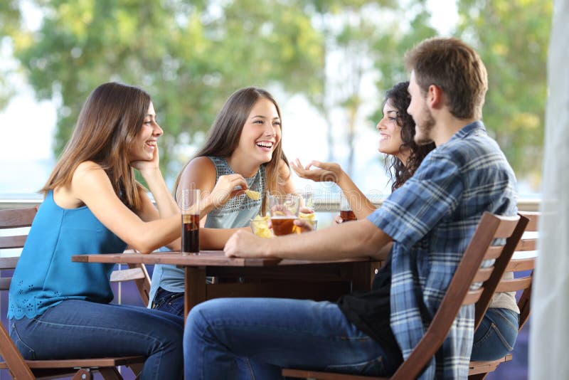 Group of four friends talking and drinking sitting in a terrace at home. Group of four friends talking and drinking sitting in a terrace at home