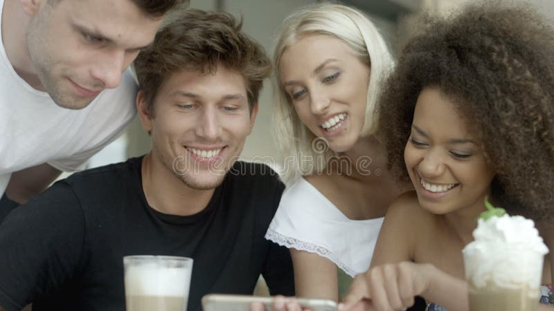 Grupo de amigos que miran las fotos en el teléfono y la risa