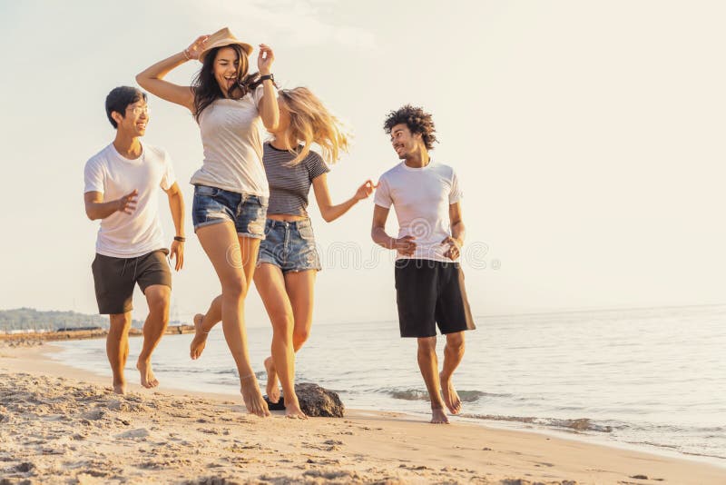Grupo de amigos que se divierten que corre abajo de la playa en la puesta del sol fotografía de archivo libre de regalías Grupo de amigos que se divierten que corre abajo de la playa en la puesta del sol fotografía de archivo libre de regalías