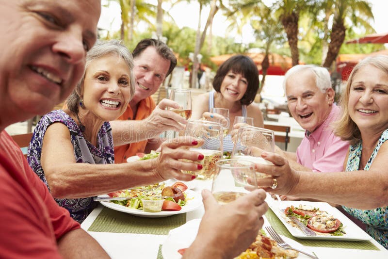 Grupo de amigos superiores que apreciam a refeição no restaurante exterior imagens de stock Grupo de amigos superiores que apreciam a refeição no restaurante exterior imagens de stock