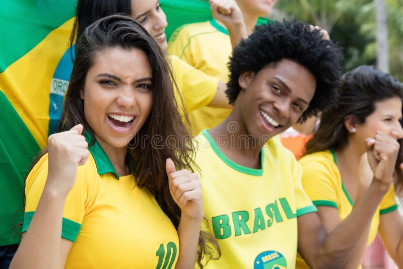 Grupo de cheering fãs de futebol brasileiros com a bandeira de Brasil
