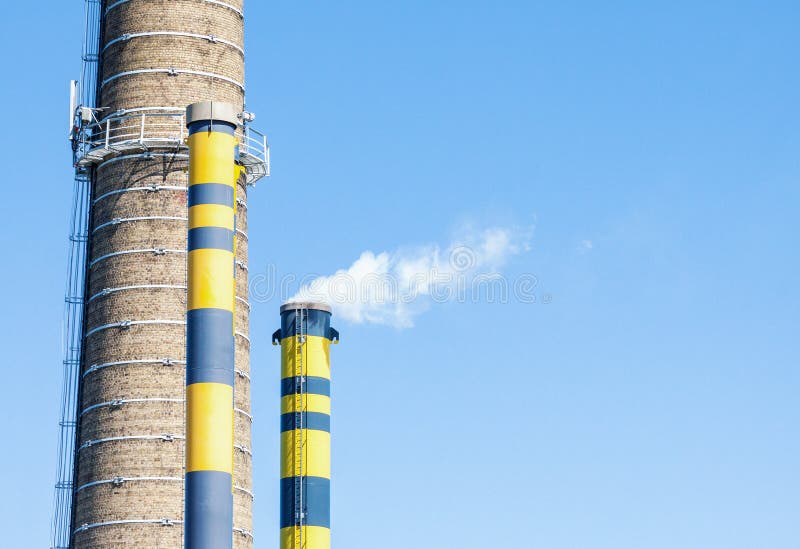 Grupo de chimeneas industriales con humo contra el cielo azul fotos de archivo Grupo de chimeneas industriales con humo contra el cielo azul fotos de archivo