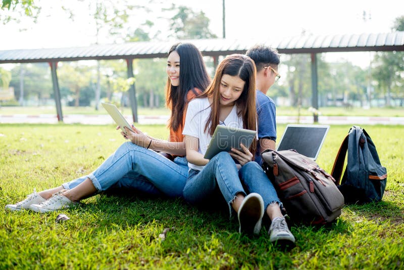 Grupo de estudante universit?rio asi?tica que usa a tabuleta e o port?til no campo de grama em fora Tecnologia e educa??o que apr fotos de stock Grupo de estudante universit?rio asi?tica que usa a tabuleta e o port?til no campo de grama em fora Tecnologia e educa??o que apr fotos de stock