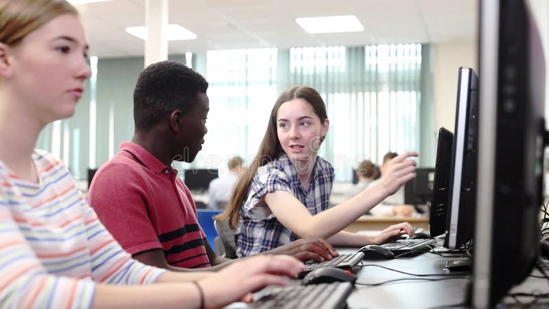 Grupo de estudantes da High School que trabalham junto na classe do computador