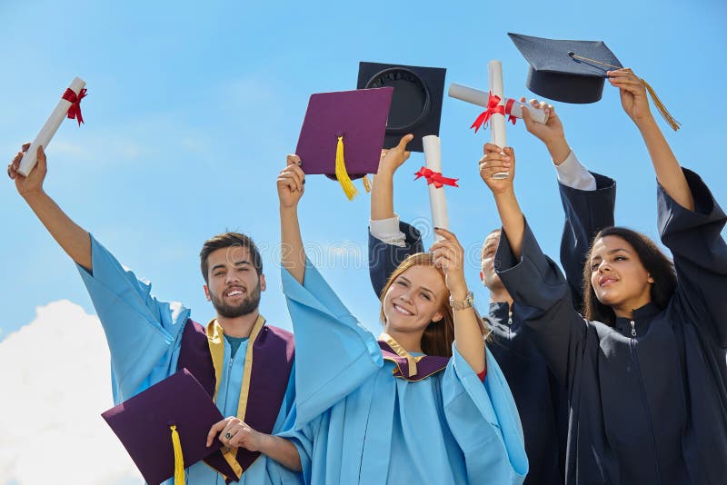 Grupo de estudantes em vestidos e em tampões da graduação fotografia de stock Grupo de estudantes em vestidos e em tampões da graduação fotografia de stock