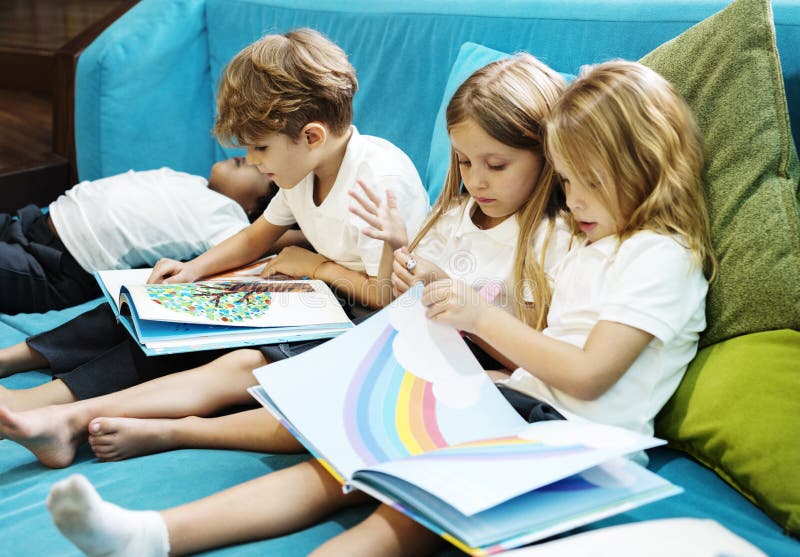Grupo de estudiantes jovenes diversos que leen el libro Toge de la historia de los niños imagen de archivo libre de regalías