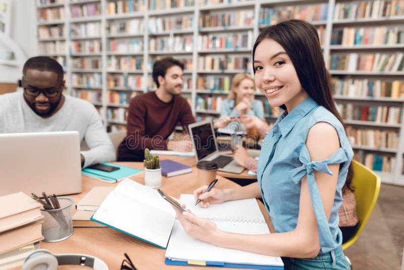 Grupo de estudiantes multiculturales étnicos en biblioteca Muchacha asiática que toma notas fotos de archivo libres de regalías Grupo de estudiantes multiculturales étnicos en biblioteca Muchacha asiática que toma notas fotos de archivo libres de regalías