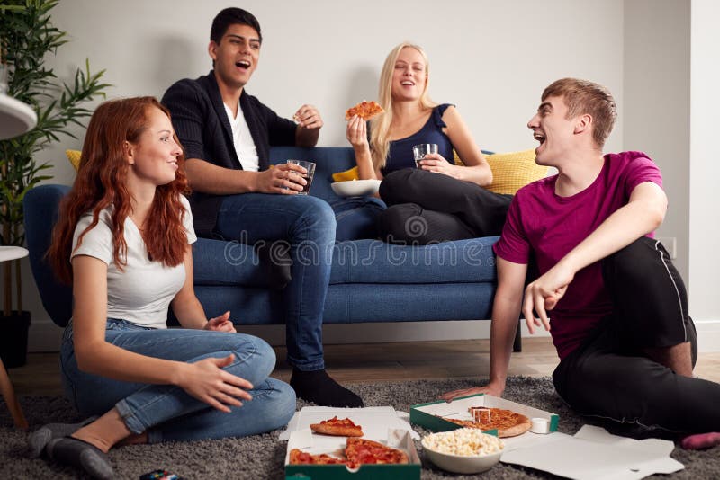 Grupo De Estudiantes Universitarios En Casa Compartida Que Tienen Noche Comyendo Pizza Juntos imagen de archivo libre de regalías
