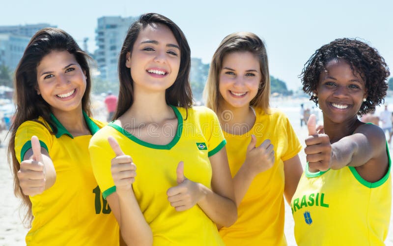 Grupo de fãs de futebol brasileiros que mostram os polegares exteriores na cidade