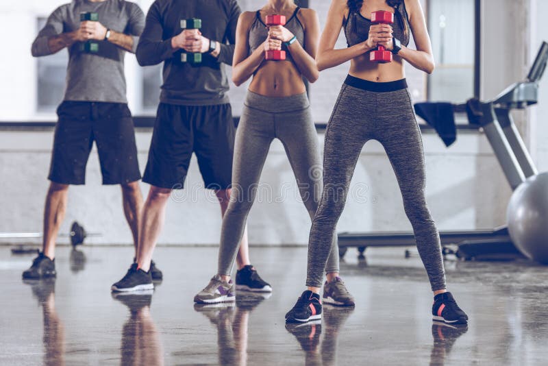 Grupo de gente joven atlética en ropa de deportes con el ejercicio de las pesas de gimnasia imagen de archivo libre de regalías Grupo de gente joven atlética en ropa de deportes con el ejercicio de las pesas de gimnasia imagen de archivo libre de regalías
