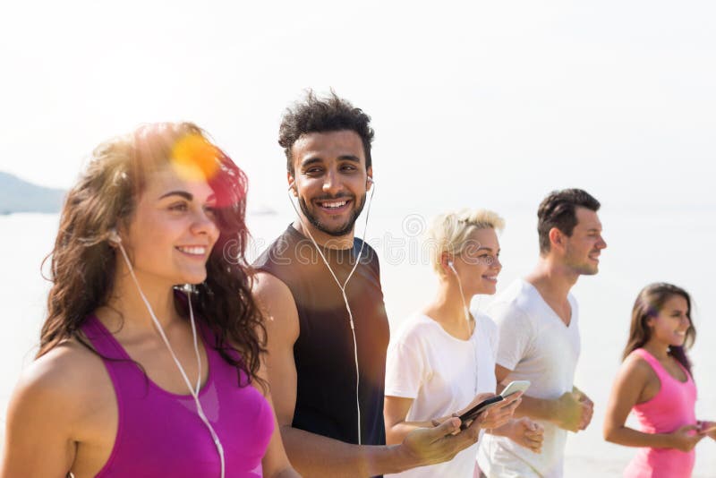 Grupo de gente joven que corre en la sonrisa feliz de la playa, de corredores del deporte de la raza de la mezcla que activan res imagenes de archivo Grupo de gente joven que corre en la sonrisa feliz de la playa, de corredores del deporte de la raza de la mezcla que activan res imagenes de archivo