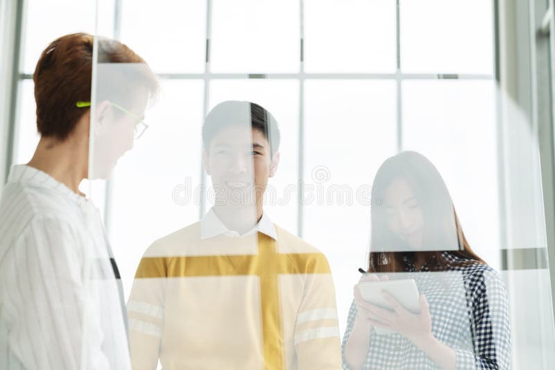 Grupo de hombres de negocios atractivos asiáticos jovenes que se colocan, hablando y escuchando el encuentro con del encargado de imagenes de archivo Grupo de hombres de negocios atractivos asiáticos jovenes que se colocan, hablando y escuchando el encuentro con del encargado de imagenes de archivo