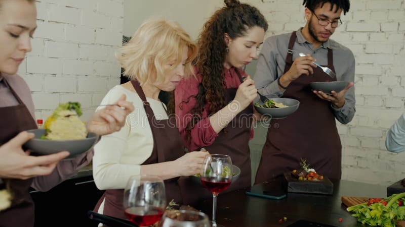 Grupo de hombres y mujeres felices comiendo deliciosas comidas después de clases magistrales culinarias