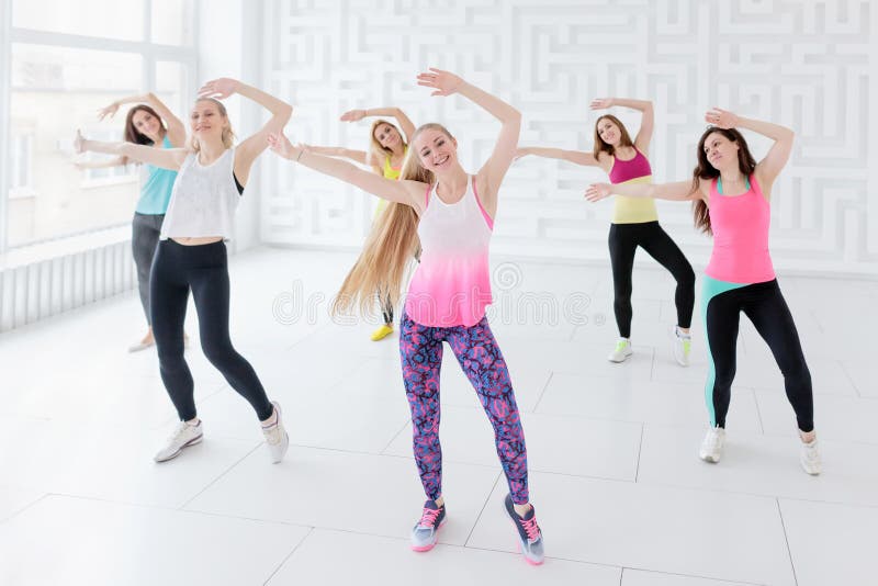 Young women posing with arms raised while having a fitness dance class. Young women posing with arms raised while having a fitness dance class
