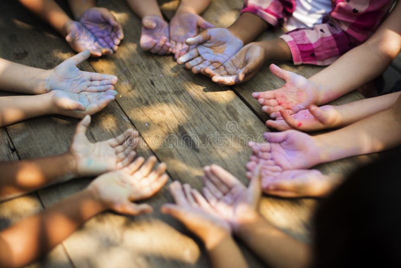 Grupo de la diversidad de niños que llevan a cabo las manos en tiza del círculo