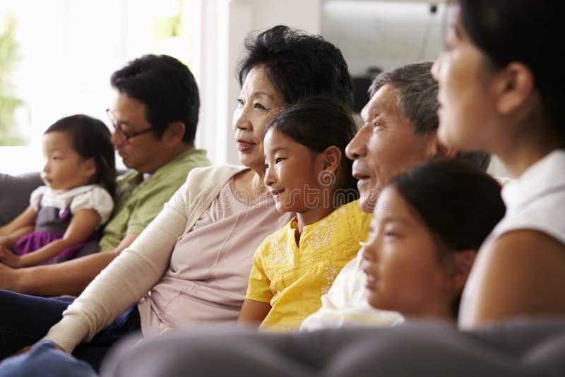 Grupo de la familia extensa en casa que ve la TV junto fotos de archivo libres de regalías Grupo de la familia extensa en casa que ve la TV junto fotos de archivo libres de regalías